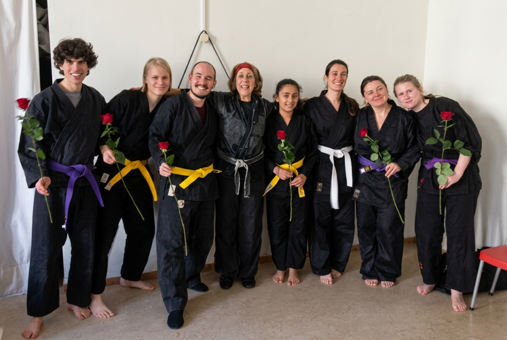 Beth Holt with Kawayan Martial Arts School students celebrating belt grading, holding red roses, Netherlands