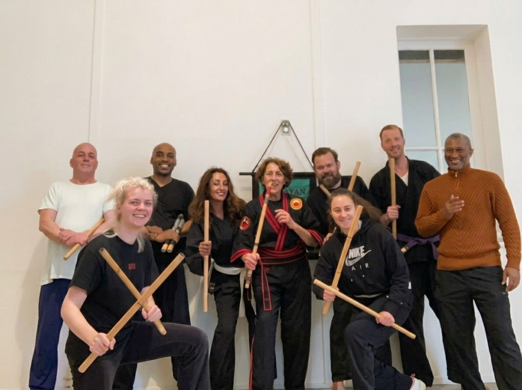 Beth Holt teaching Modern Arnis Filipino martial arts to a mixed group of adult students holding rattan canes, Kawayan Martial Arts School Gemert